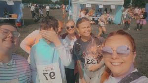 A group of team members and young people covered in powder paint after completing the race.